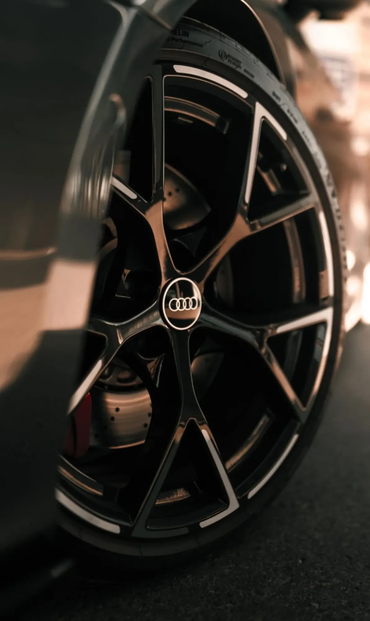 Gloss black Audi RS alloy wheel and red brake caliper in warm evening light