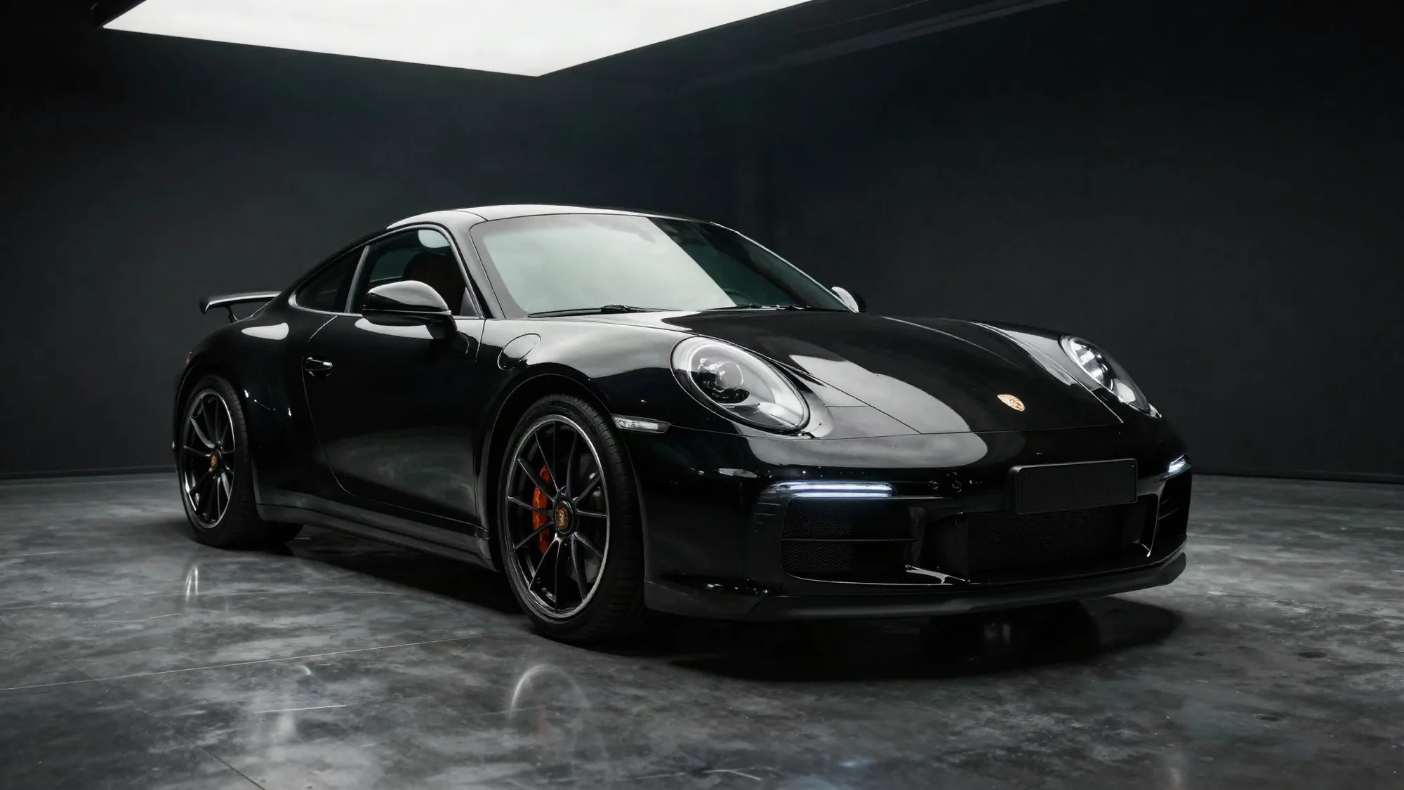 Freshly detailed gloss black Porsche 911 in a dark luxury detailing studio